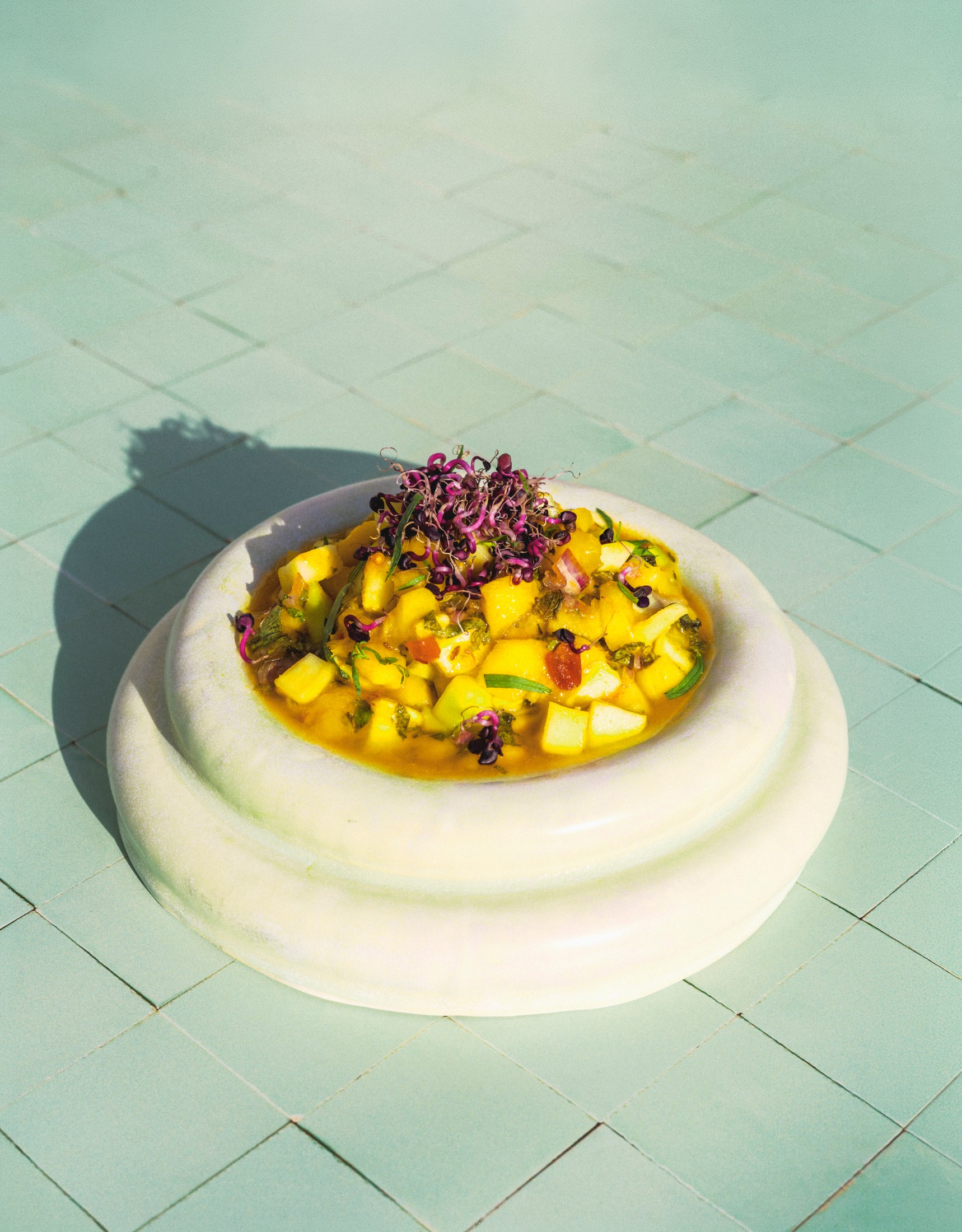 Overhead shot of a mango salsa chutney dip in a small bowl on a pale tiled surface