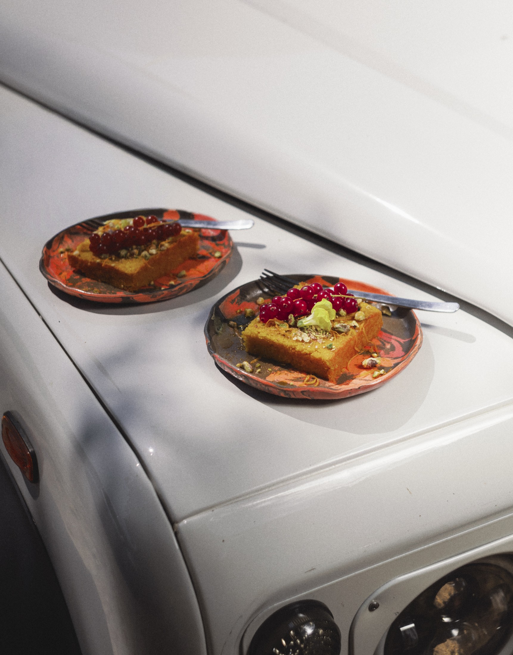 Two plates of polenta cake balanced on the roof of a parked car