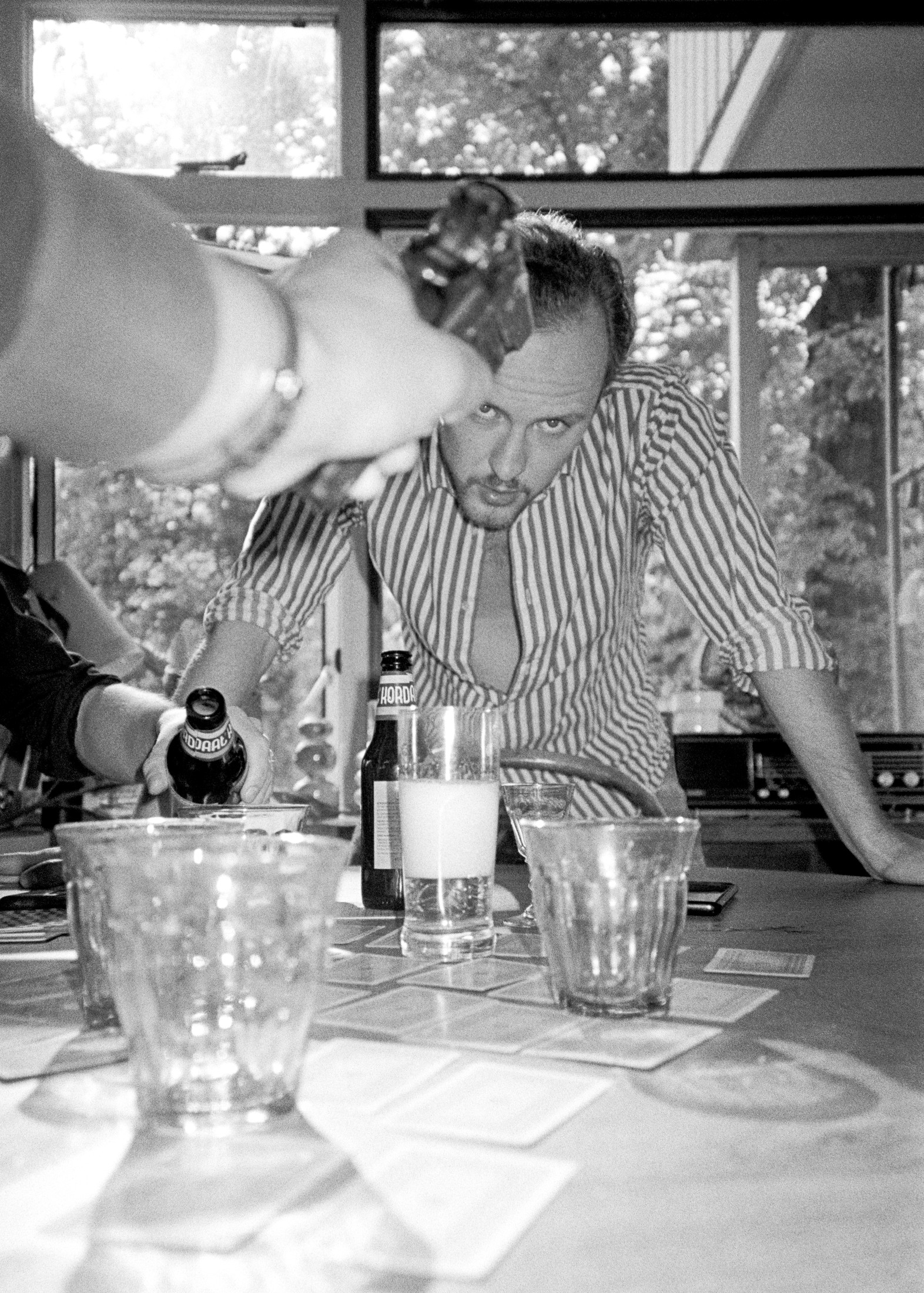Candid portrait of someone reaching for glasses at a window table