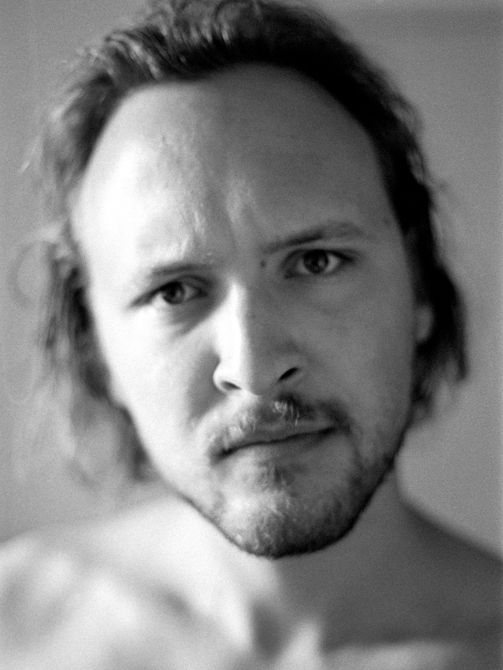 Black-and-white headshot of a bearded man looking directly at the camera