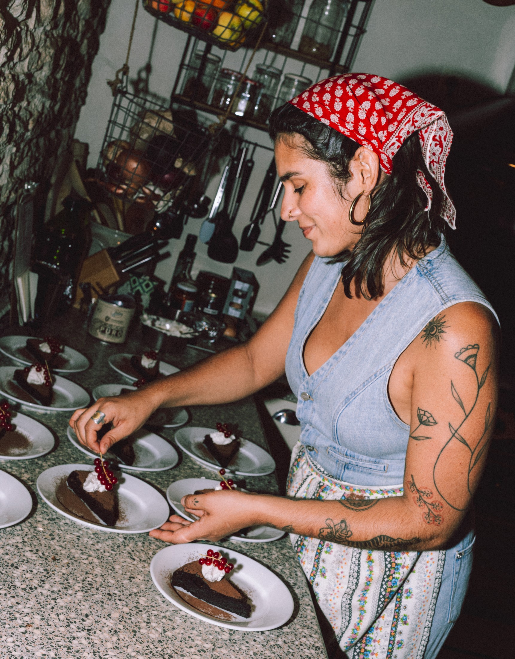 Candid portrait of a woman in an apron plating dessert in a busy kitchen