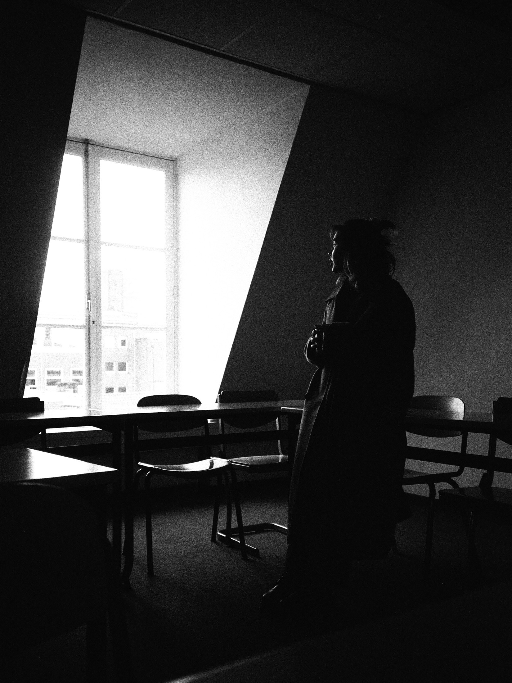 Silhouetted figure standing in an empty sunlit room